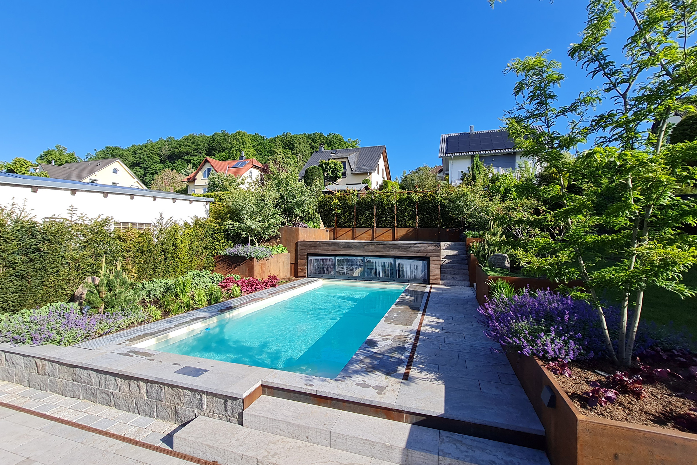 Pool mit heller Sandfolie und harmonischer Gartengestaltung in einem Wohngebiet