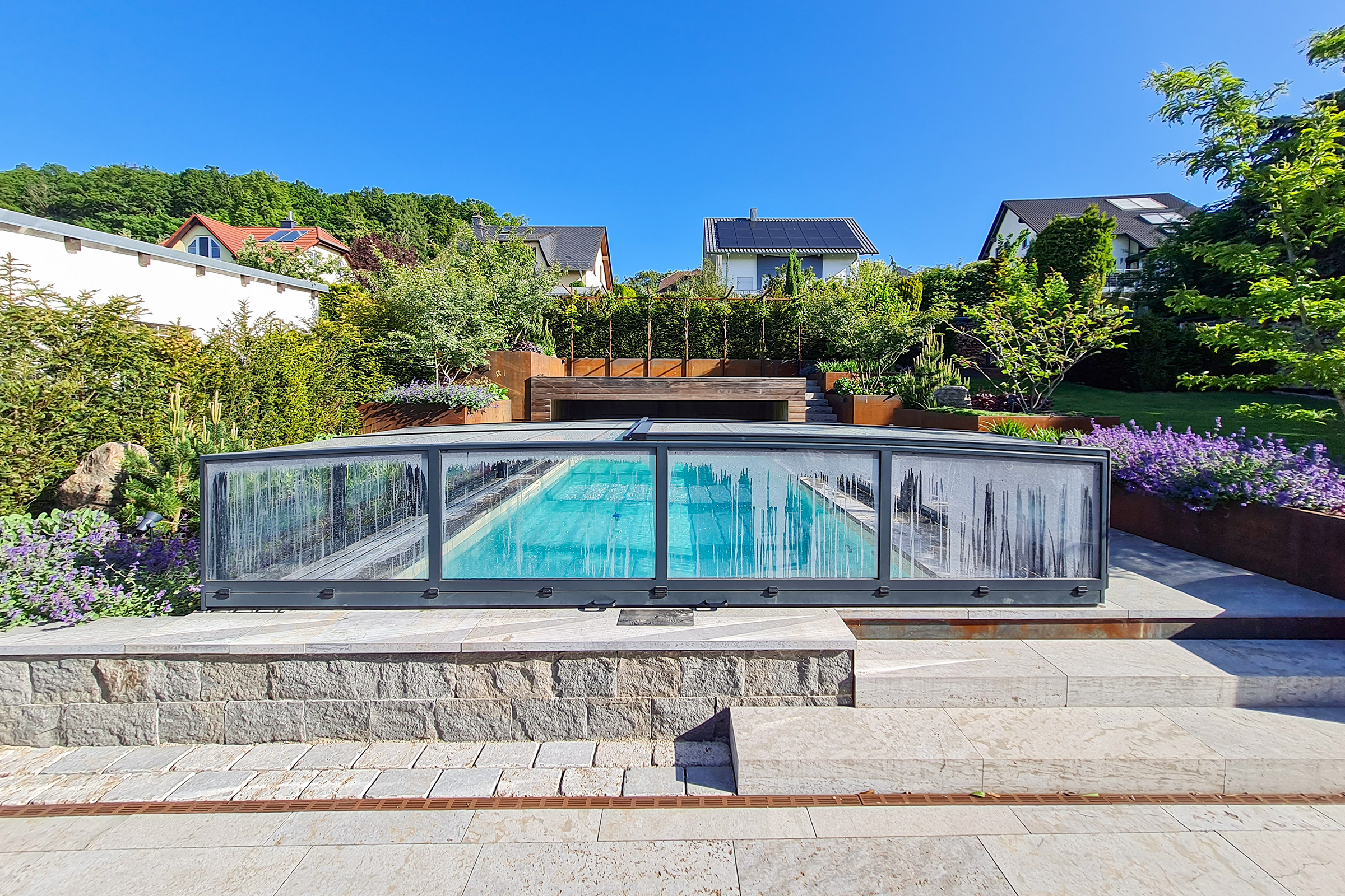 Blick auf Massivpool mit Poolüberdachung und harmonisch eingebundener Gartengestaltung