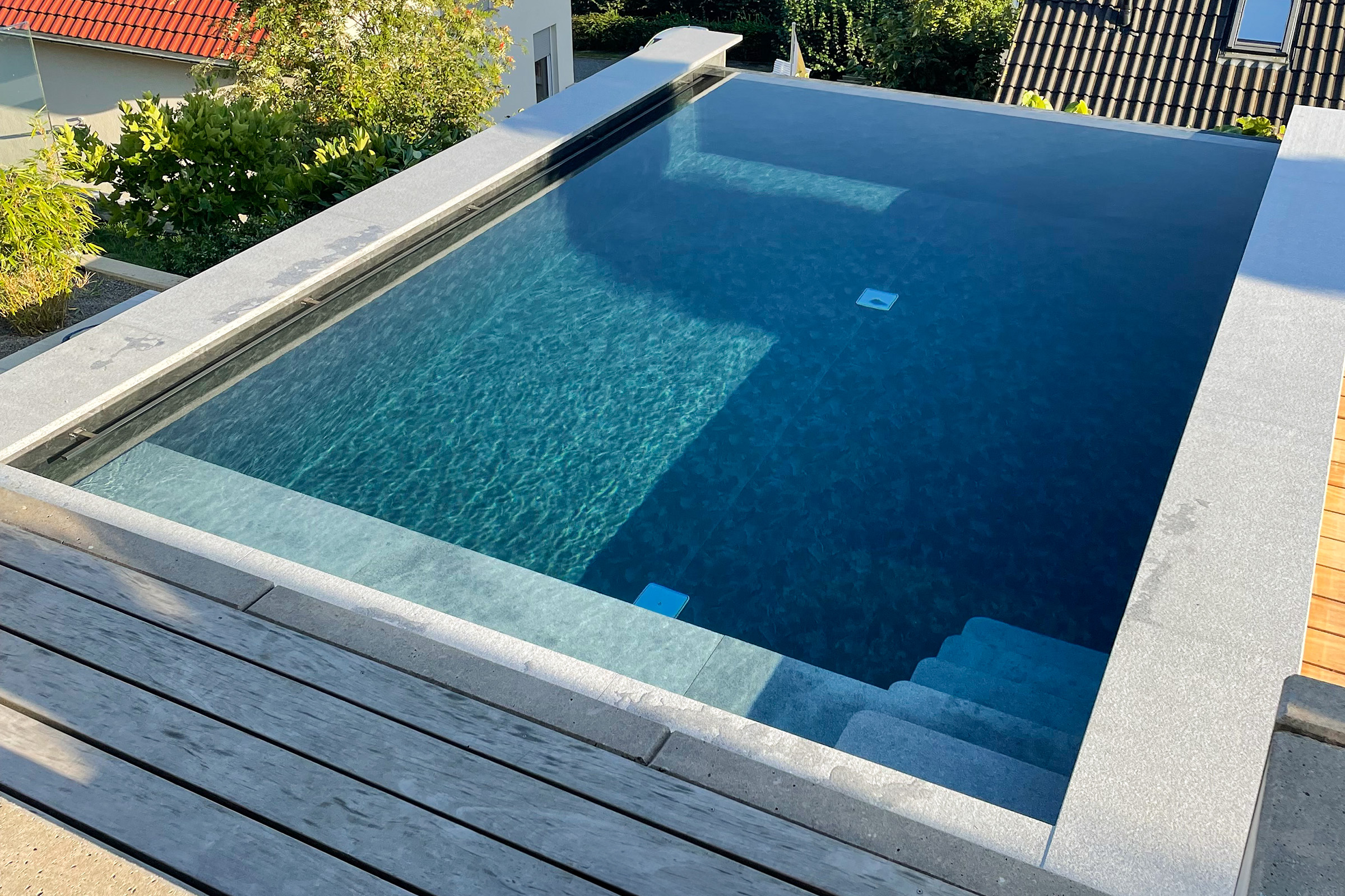 betonbecken-mit-infinityrinne-und-freitragender-treppe-aus-granit