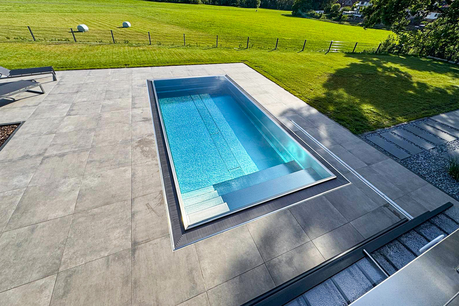 Edelstahl Überlaufpool mit integrierter Sitzbank und modernem Terrassenbelag