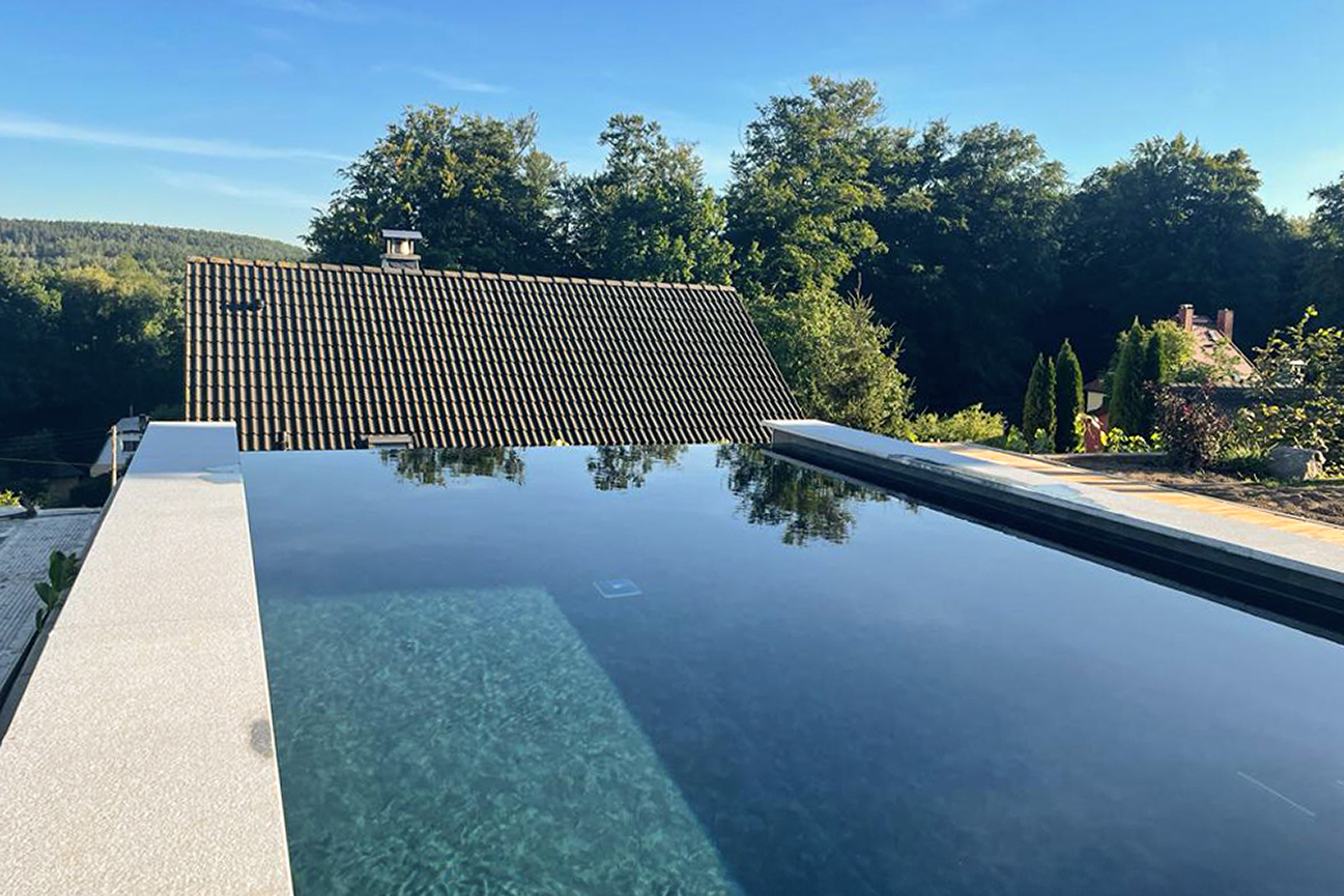 betonbecken-mit-infinityrinne-und-freitragender-treppe-aus-granit